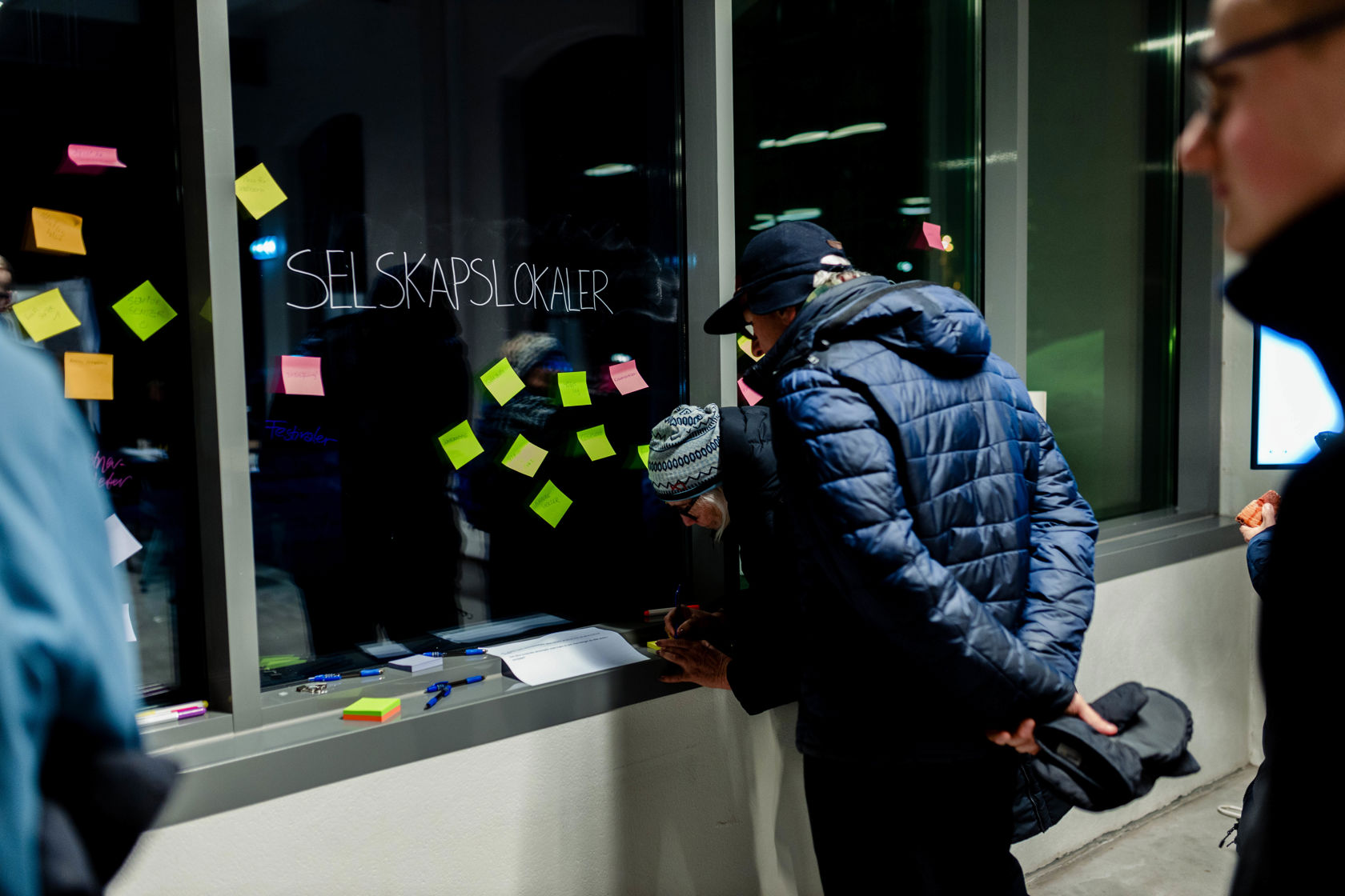 Mann leser på post-it lapper som henger på et vindu