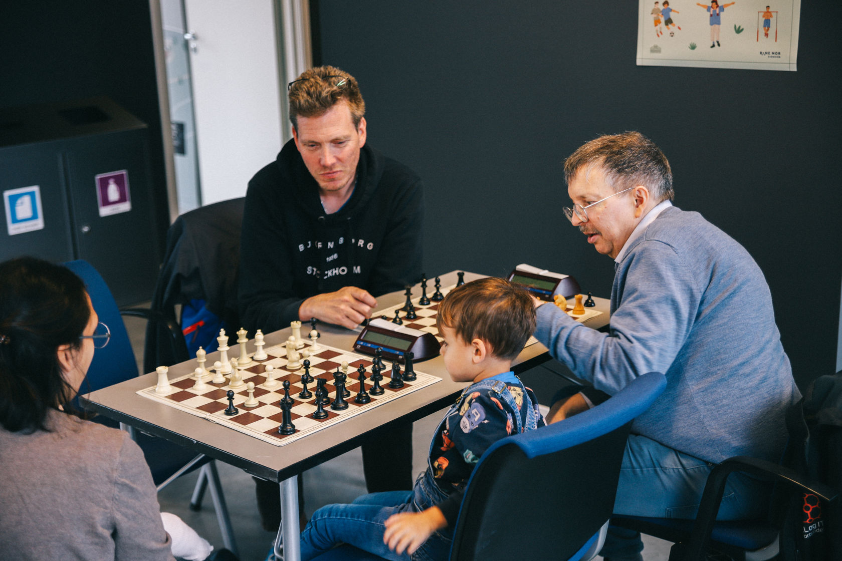 Tre voksne mennesker og et barn spiller lynsjakk