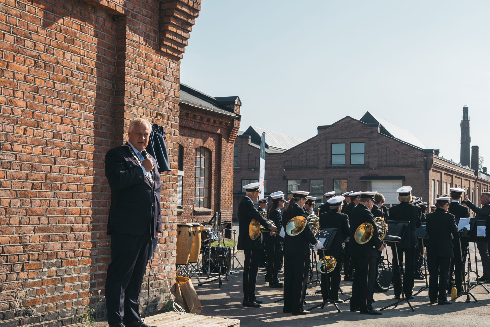 Mann på scene, korps som spiller ved siden av